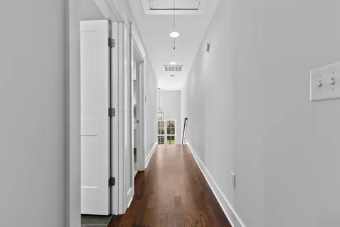 a view of a hallway with wooden floor and a bathroom