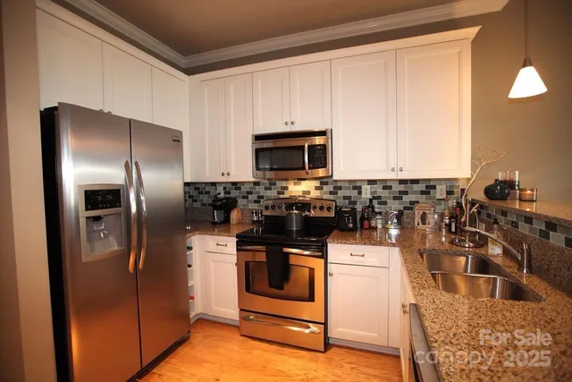 a kitchen with stainless steel appliances granite countertop a refrigerator a stove a sink and a microwave