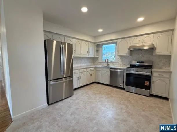 a kitchen with stainless steel appliances granite countertop a refrigerator sink and stove