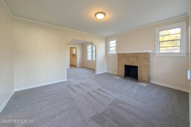 an empty room with windows and fireplace