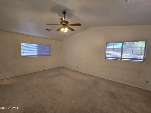 an empty room with windows and fan