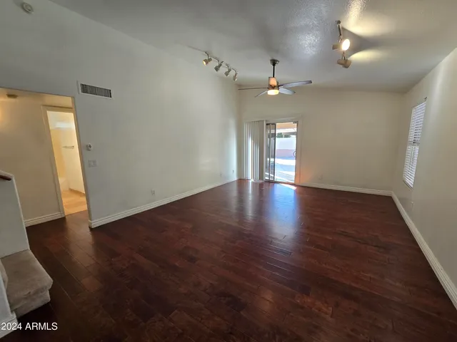an empty room with wooden floor and ceiling fan