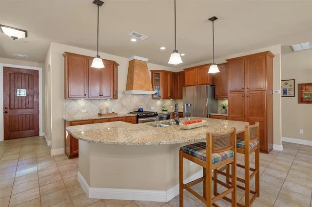 a kitchen with kitchen island granite countertop a sink a center island a stove cabinets and a chandelier