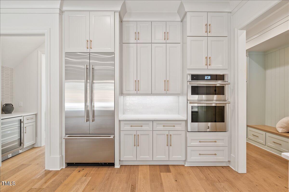 7516 Grist Mill Road Raleigh, NC 27615 - Photo 24 of 83 a kitchen with stainless steel appliances white cabinets and wooden floors