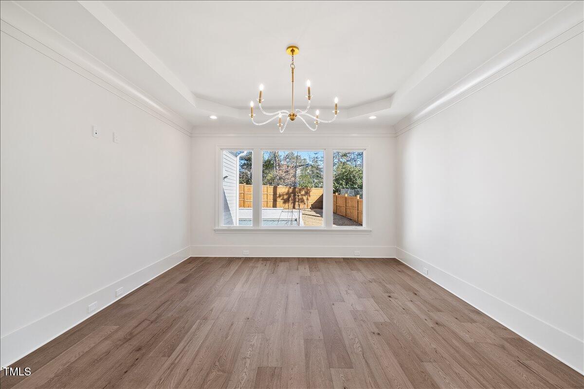 7516 Grist Mill Road Raleigh, NC 27615 - Photo 38 of 83 an empty room with wooden floor chandelier and windows