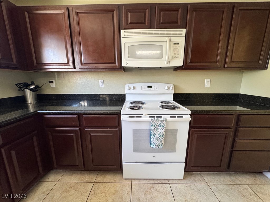 504 I Avenue Boulder City, NV 89005 - Photo 19 of 60 Kitchen with white appliances, dark stone countertops, dark brown cabinets, and light tile patterned flooring