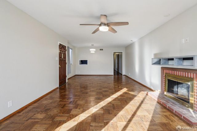 a view of a livingroom with a fireplace a ceiling fan and windows