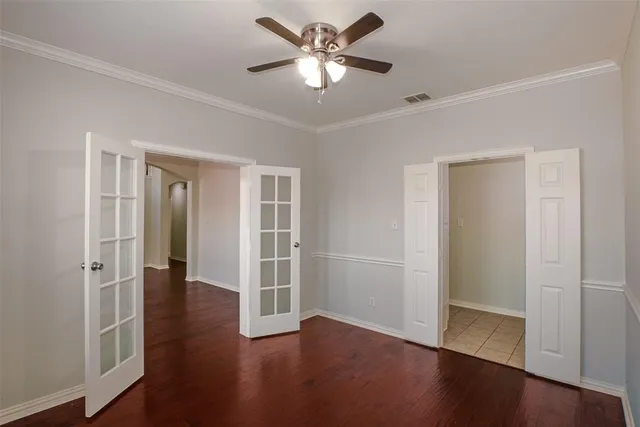 an empty room with wooden floor and a ceiling fan
