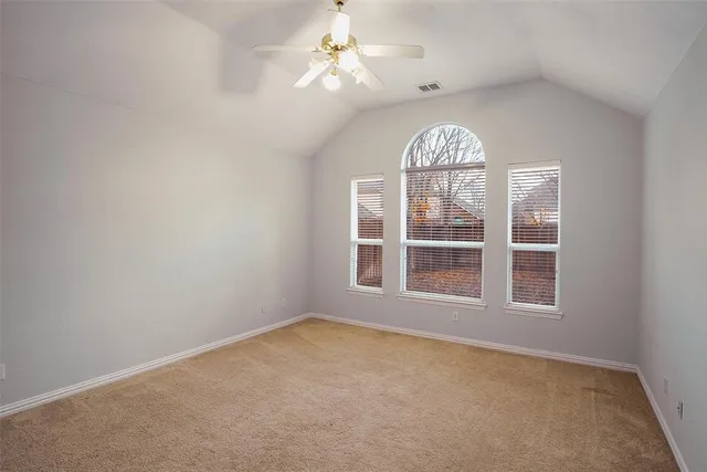 an empty room with a chandelier fan and windows