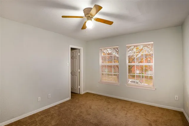 a view of an empty room with chandelier fan and a window