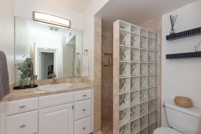 a bathroom with a granite countertop sink toilet and shower