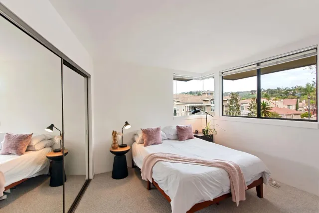 a bedroom with a bed and large windows