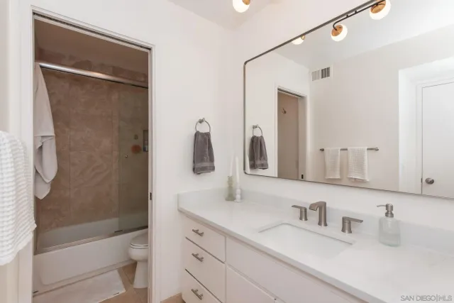 a bathroom with a granite countertop sink a toilet and shower