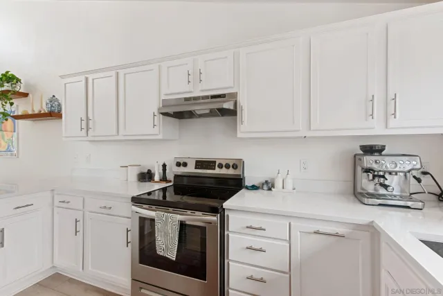 a kitchen with white cabinets and appliances
