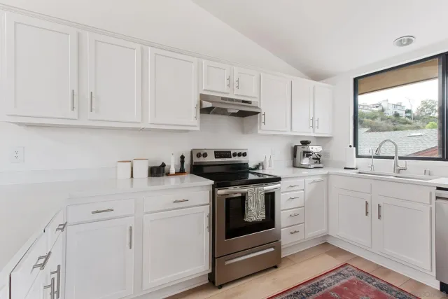 a kitchen with white cabinets and appliances