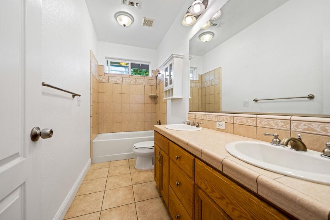 8418 Placer Road Redding, CA 96001 - Photo 4 of 47 a bathroom with a granite countertop sink a toilet a mirror a bathtub and shower