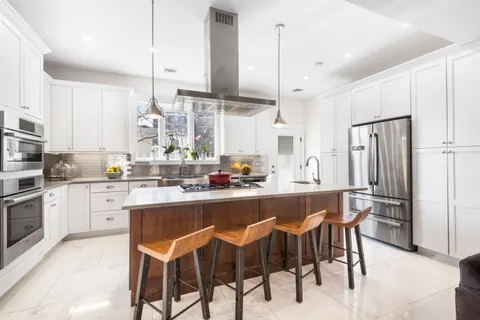 a kitchen with a sink a stove a refrigerator and white cabinets with wooden floor