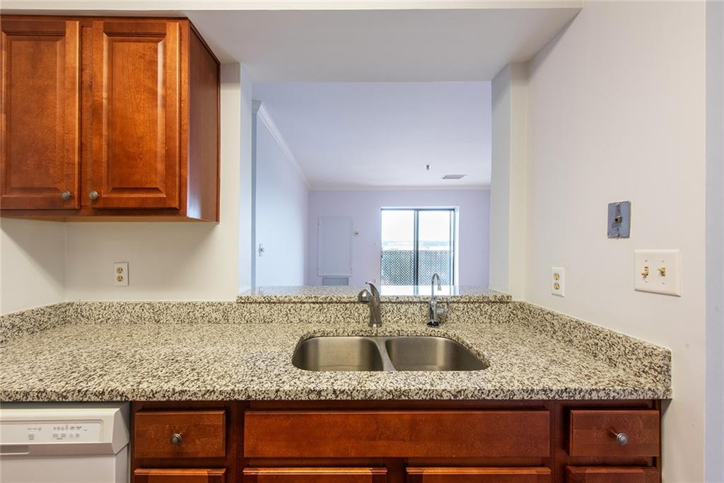 300 Johnson Ferry Road, Unit B808 Atlanta, GA 30328 - Photo 13 of 41 a kitchen with granite countertop a sink a stove and a wooden cabinets