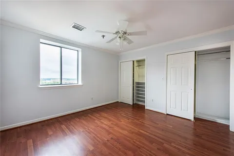 an empty room with wooden floor chandelier fan and windows