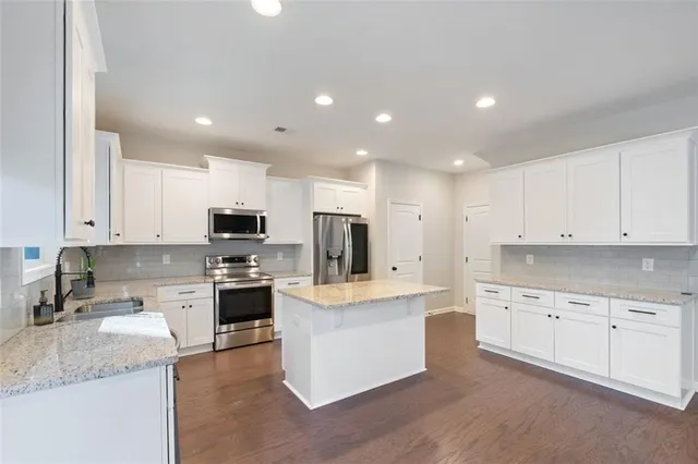 a large kitchen with stainless steel appliances granite countertop a refrigerator and a stove top oven