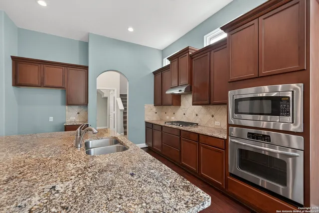 a kitchen with stainless steel appliances granite countertop a stove a sink and a microwave