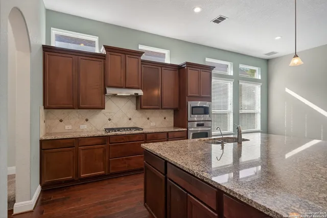 a kitchen with stainless steel appliances granite countertop wooden cabinets a sink and dishwasher