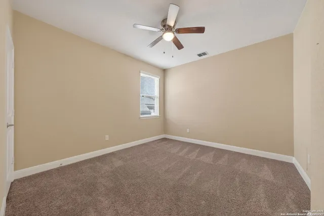 an empty room with windows and ceiling fan