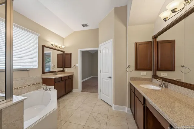 a large bathroom with a granite countertop double vanity sink a bathtub and mirror