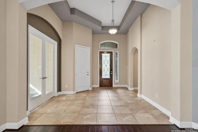 an empty room with chandelier fan and windows