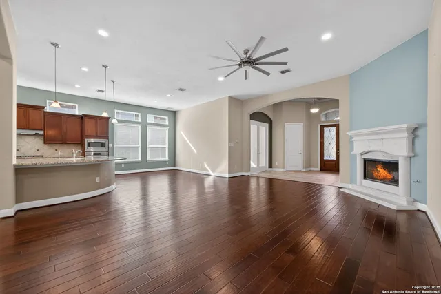 a view of a kitchen and an empty room with wooden floor and a kitchen