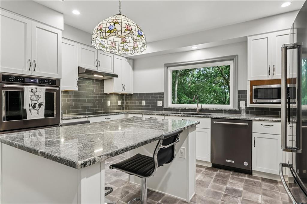 806 Belmont Road Butler, PA 16001 - Photo 17 of 49 a kitchen with stainless steel appliances granite countertop a stove top oven a sink dishwasher a dining table and chairs with wooden floor