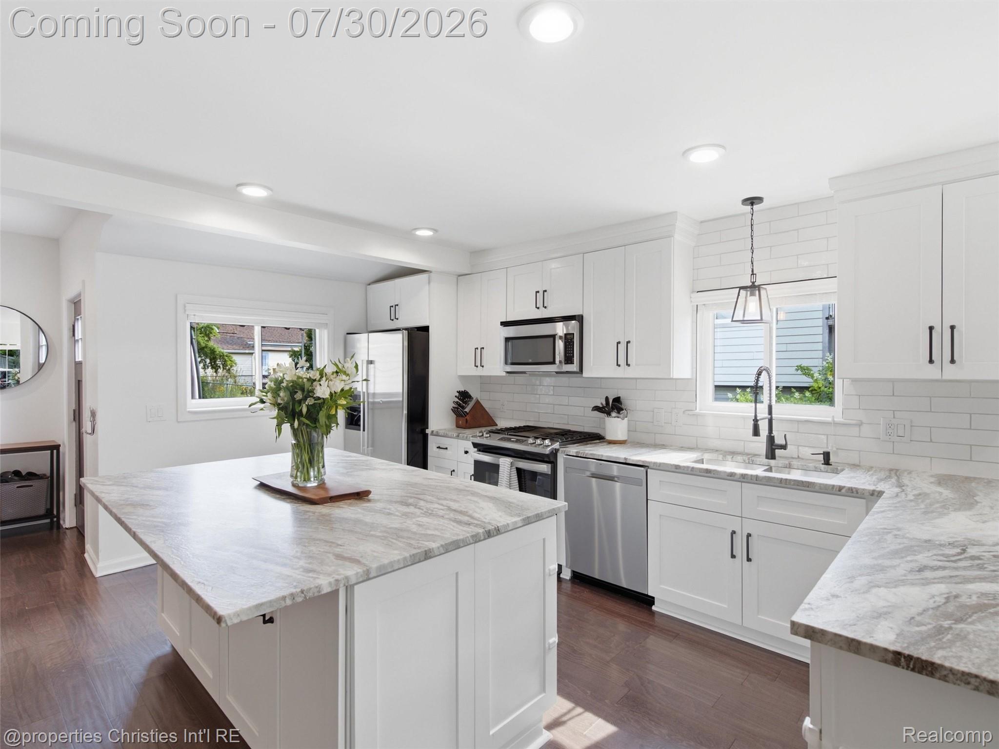 1642 Harvard Road Berkley, MI 48072 - Photo 9 of 29 Kitchen featuring an oversized island, white shaker cabinetry, stainless steel appliances, and wood-finish flooring