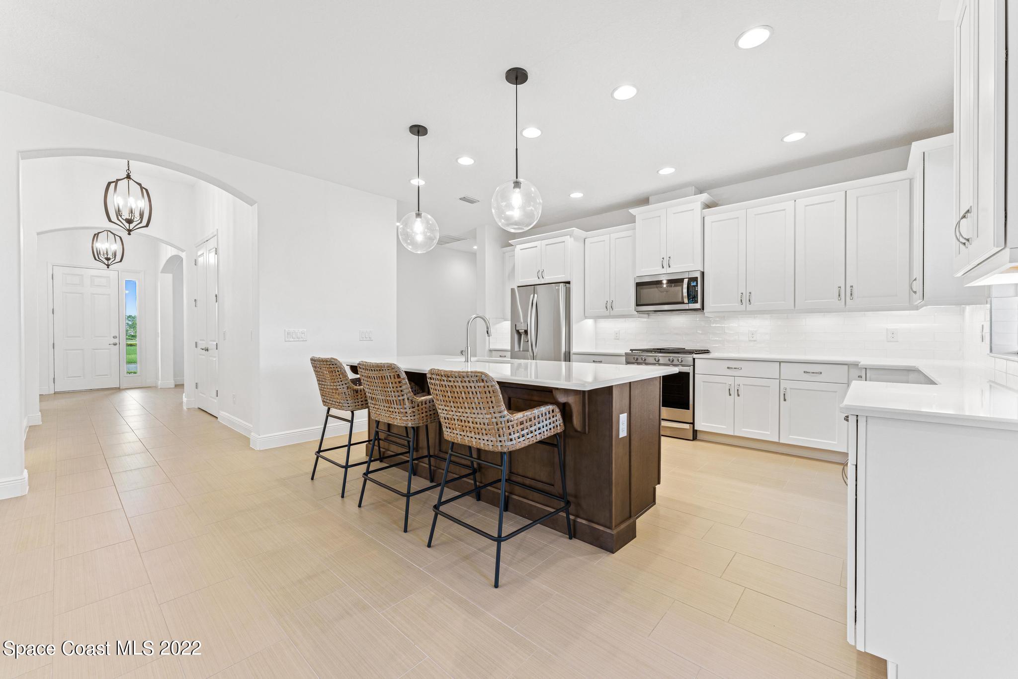 3231 Casterton Drive Melbourne, FL 32940 - Photo 11 of 88 a kitchen with kitchen island a dining table chairs and white cabinets