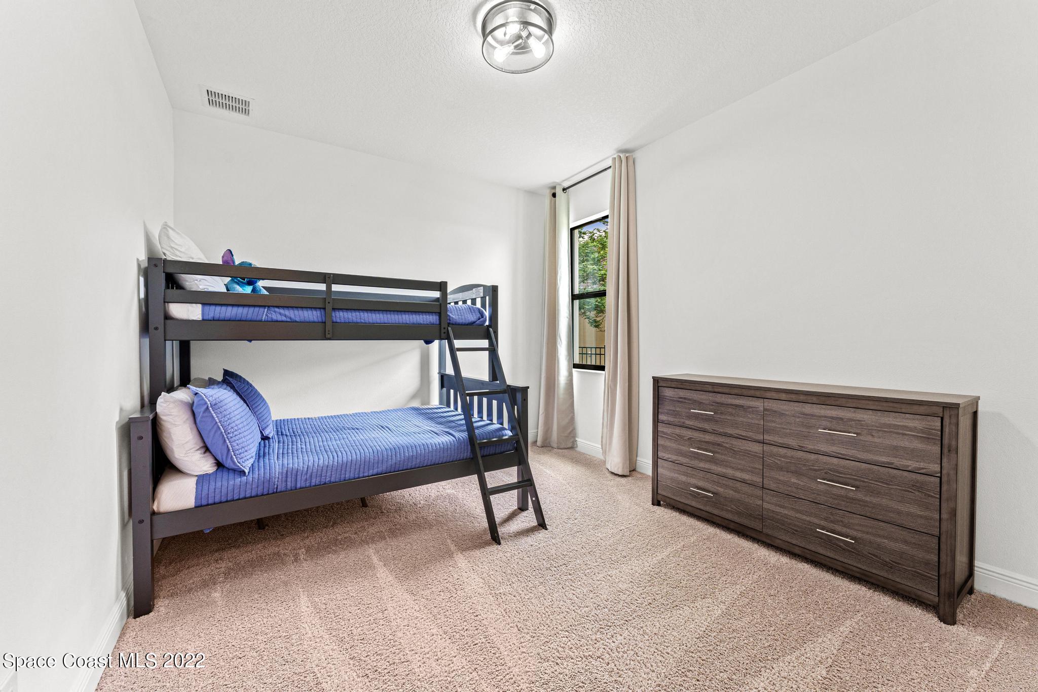 3231 Casterton Drive Melbourne, FL 32940 - Photo 45 of 88 a bedroom with a bed and a chandelier