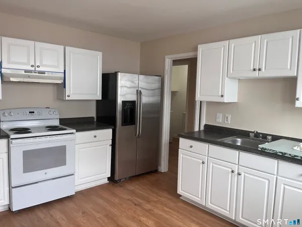 a kitchen with granite countertop white cabinets and white appliances