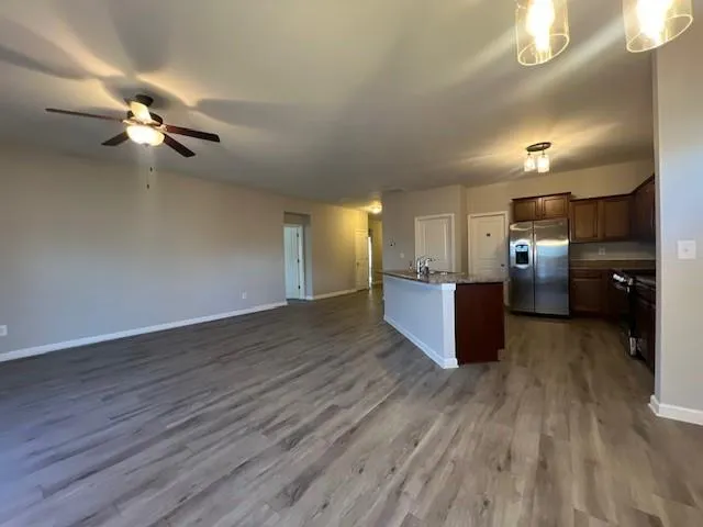 an empty room with wooden floor chandelier fan and windows