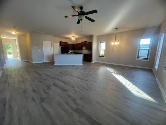 an empty room with wooden floor ceiling fan and windows