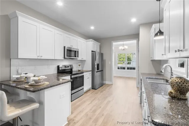 a kitchen with granite countertop a stove top oven a sink dishwasher a dining table and chairs with wooden floor