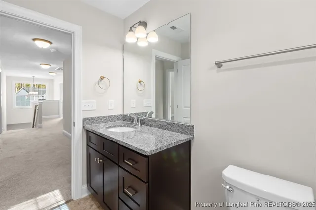 a bathroom with a granite countertop sink a toilet a mirror and shower