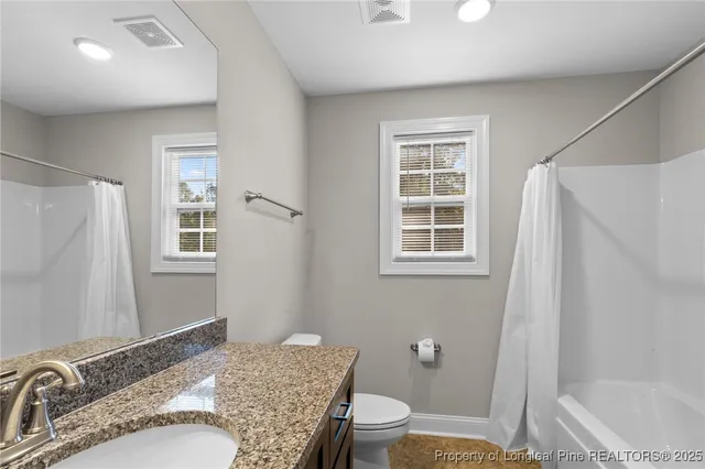 a bathroom with a granite countertop sink toilet a mirror and shower