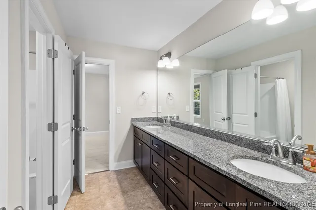 a bathroom with a granite countertop double vanity sink and mirror