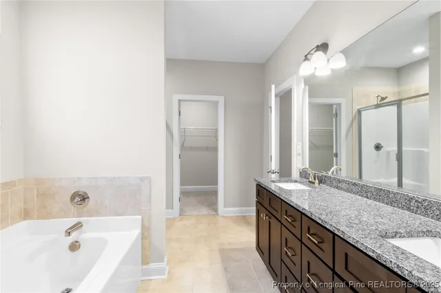 a bathroom with a granite countertop double vanity sink and mirror with bathtub