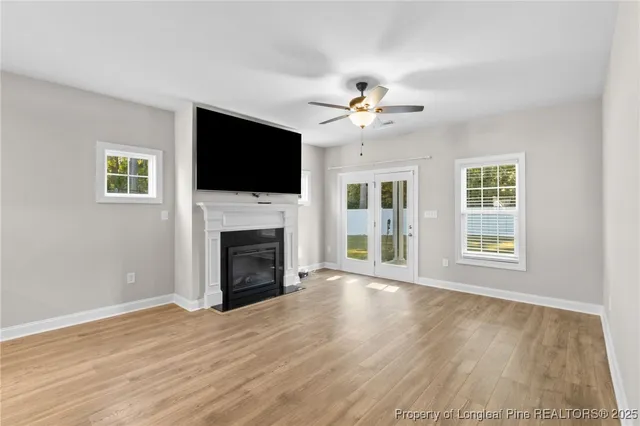 a view of a livingroom with a fireplace a ceiling fan and windows