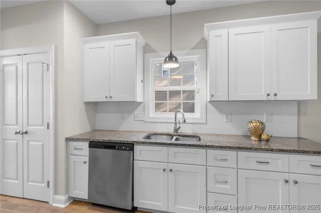 a kitchen with stainless steel appliances granite countertop white cabinets and a sink