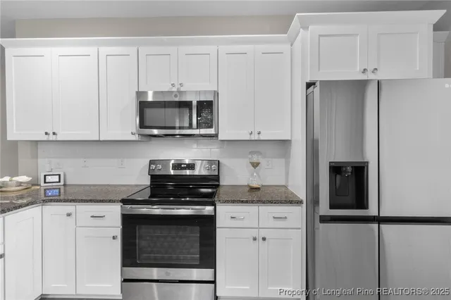 a kitchen with granite countertop white cabinets and stainless steel appliances