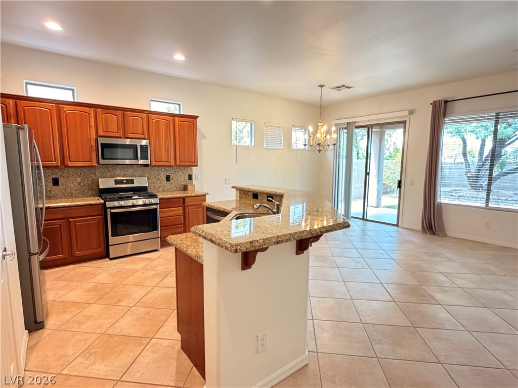 16 Caprington Road Henderson, NV 89052 - Photo 2 of 16 Gleaming tile floors and granite countertops define this open kitchen and dining area.