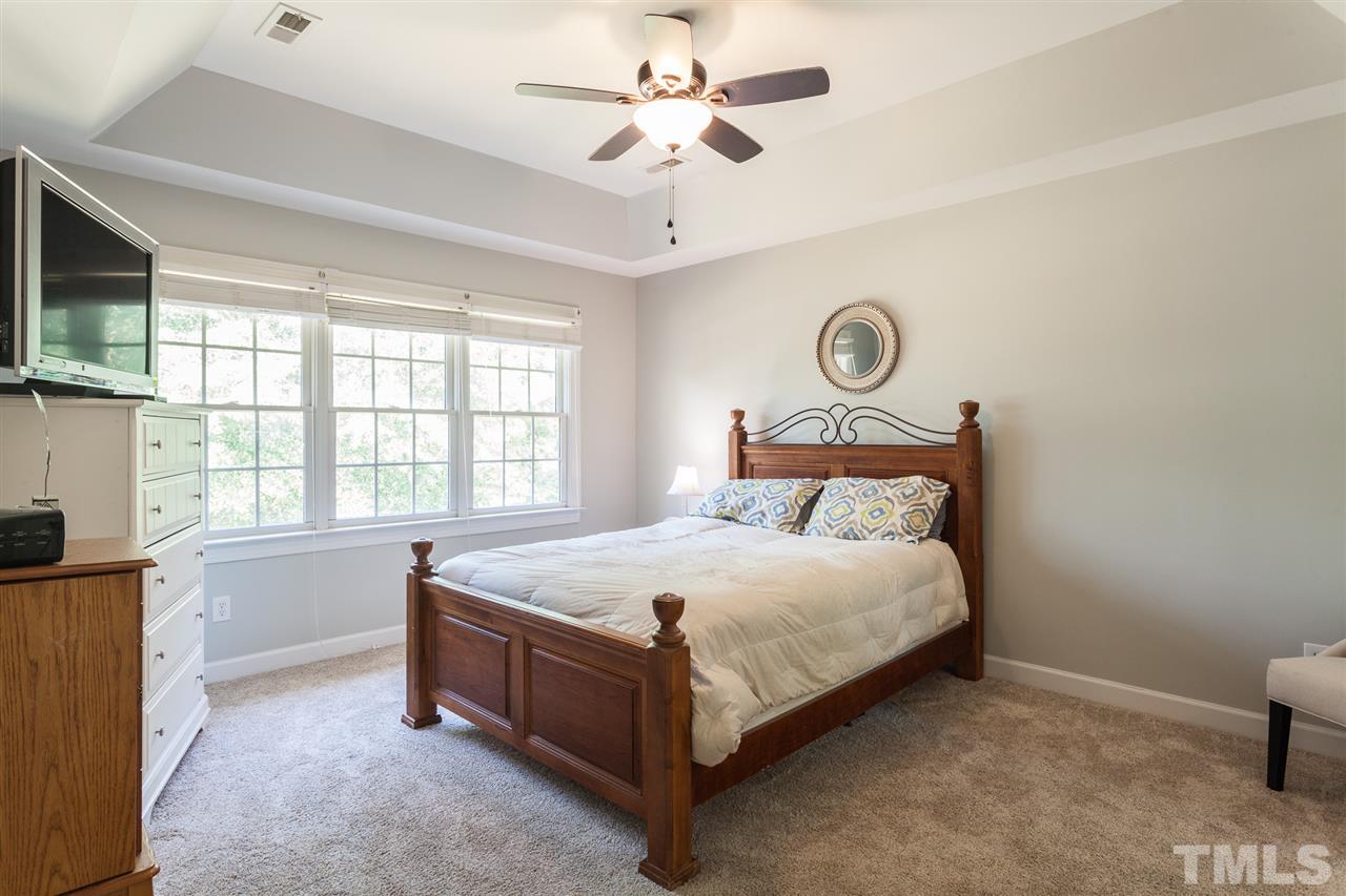 2613 Lizei Street Raleigh, NC 27616 - Photo 19 of 25 a large bed sitting in a room next to a window with a chandelier