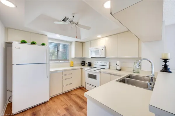a kitchen with a sink a refrigerator and white cabinets