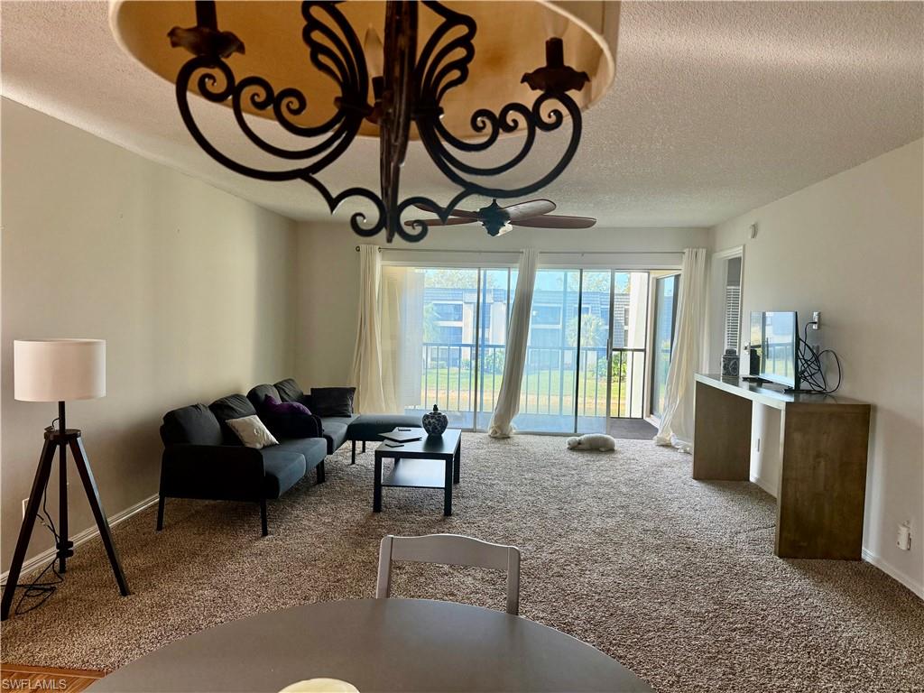 1645 Spoonbill Lane, Unit C Naples, FL 34105 - Photo 30 of 50 Carpeted living area featuring a textured ceiling and a chandelier