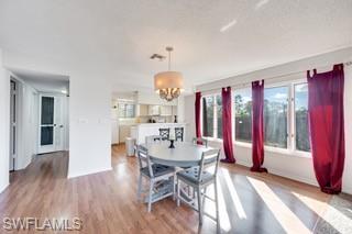 1645 Spoonbill Lane, Unit C Naples, FL 34105 - Photo 6 of 50 Dining space with light wood-type flooring, a chandelier, and a textured ceiling